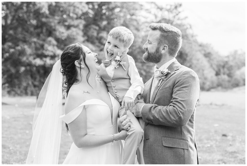 groom, bride, and bride's son laughing during family portraits after wedding ceremony