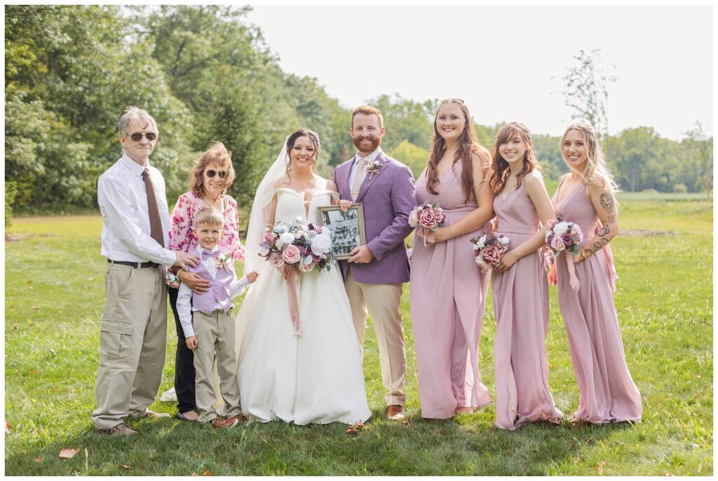 bride posing with her family outside for portraits at wedding venue