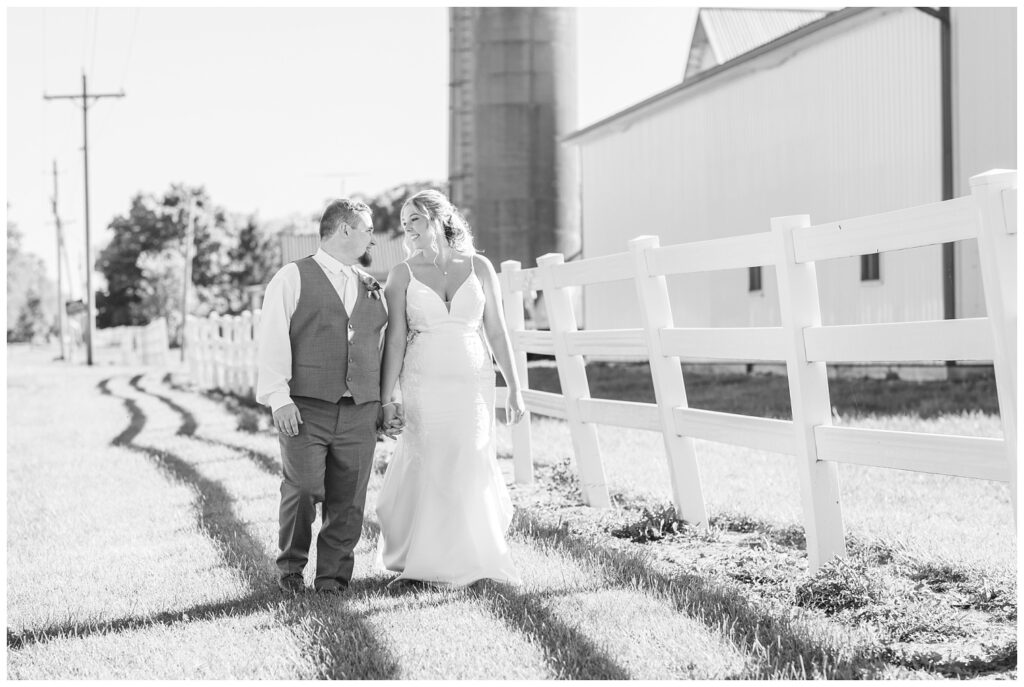 wedding coupe holding hands and walking next to a white fence in Norwalk, Ohio