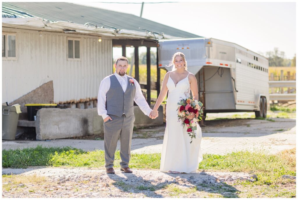 bride and groom holding hands on the groom's family dairy farm in Ohio