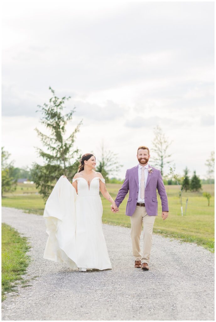 wedding couple holding hands and walking on a gravel path at Ohio reception venue