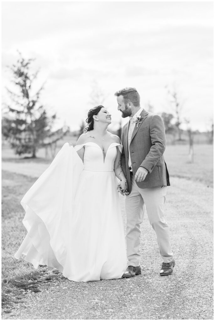 wedding couple holding hands and walking on a gravel path at northwest Ohio reception venue