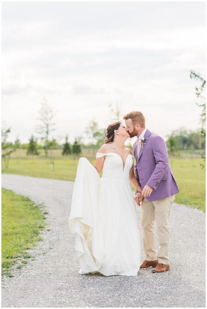 wedding couple share kiss while posing on a gravel path at northwest Ohio venue