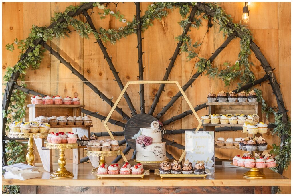 full dessert display of cake and cupcakes sitting on a wooden table with trays