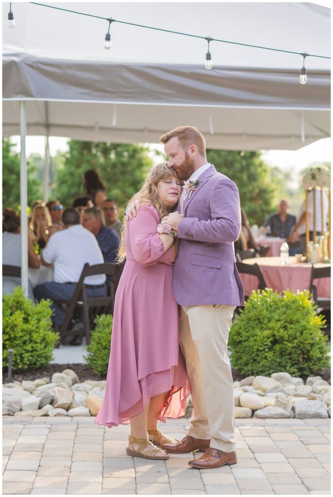 groom and his mom share a sweet dance together during the wedding reception outside