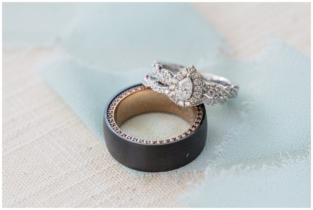 bride and groom's rings sitting on a green ribbon and beige mat