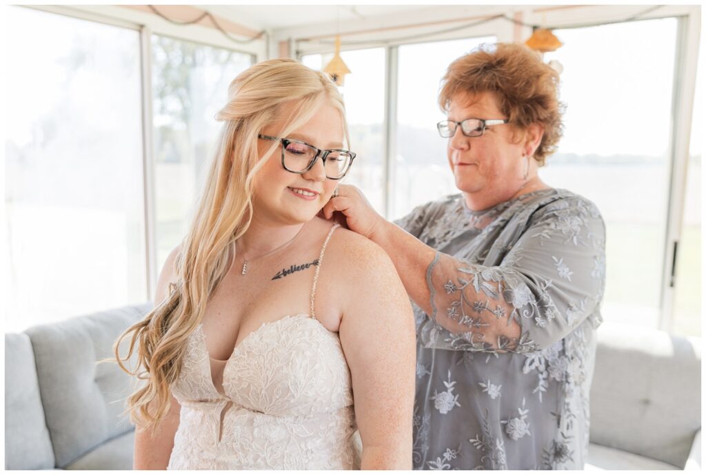 bride's mom helping the bride put on her necklace in the sunroom