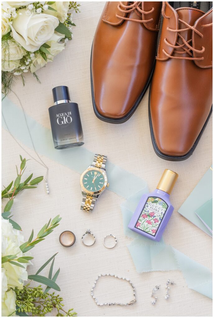 bride and groom's cologne and perfume next to the groom's shoes and watch