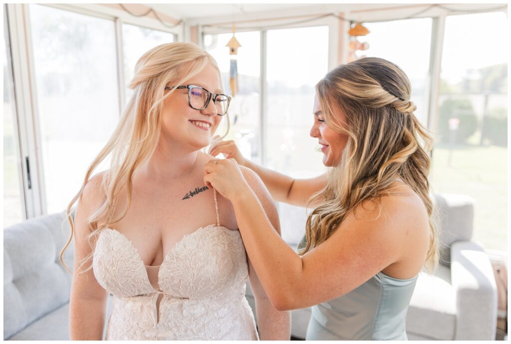 bridesmaid adjusting the bride's dress straps on the sunroom porch in Bowling  Green, Ohio