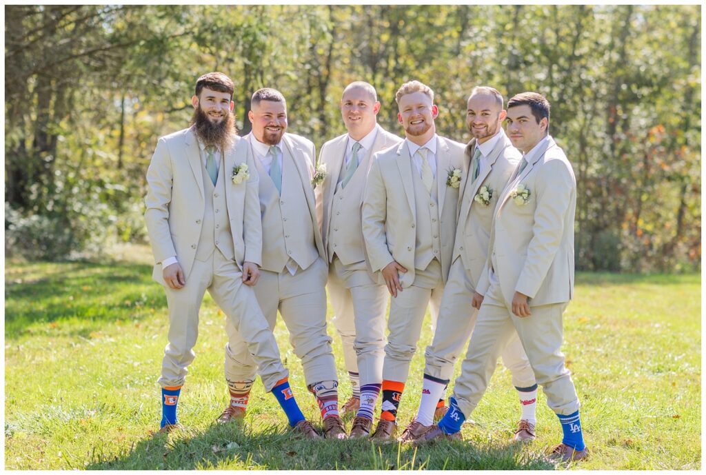 groomsmen showing off their favorite team socks with their beige suits 