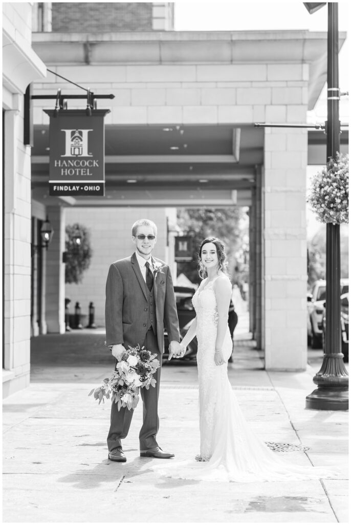 bride and groom holding hands outside the entrance to The Hancock Hotel