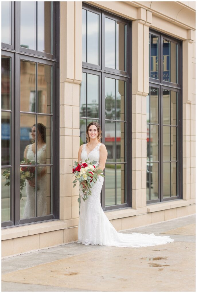 bride posing with her bouquet in front of the large windows outside at The Hancock Hotel