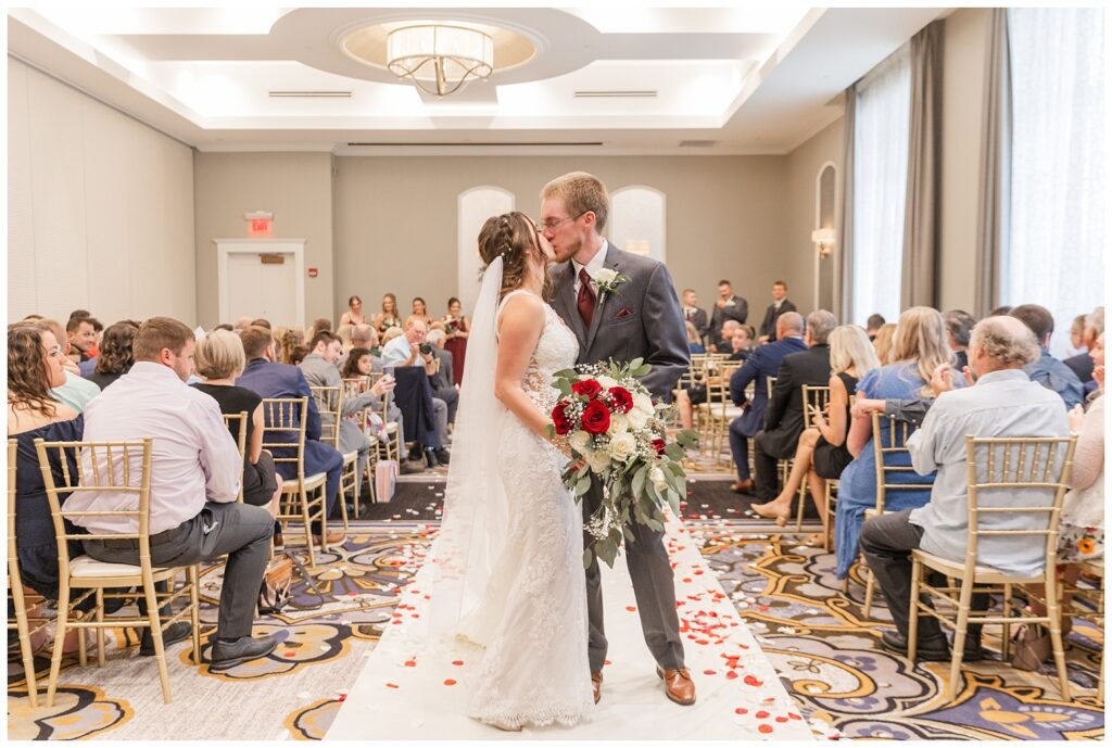 bride and groom kissing down the aisle at fall hotel wedding