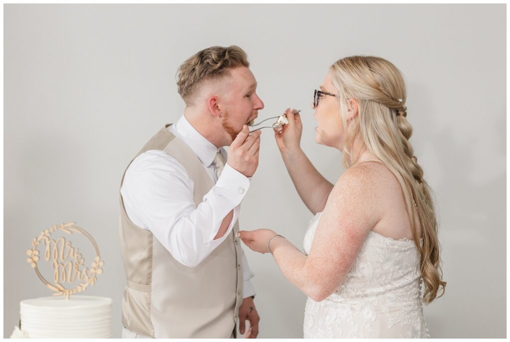 bride and groom tasting their wedding cake at reception at Stacy's Place