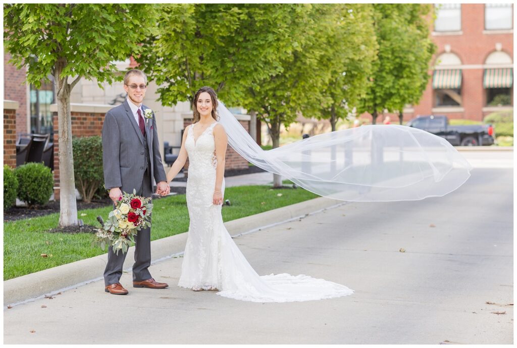 bride and groom holding hands while the bride's veil swings in the wind