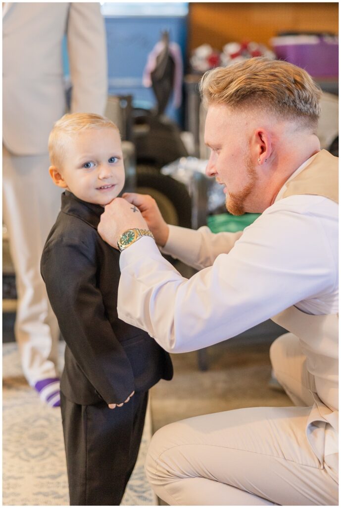 groom adjusting the ring bearer's shirt while getting ready for the wedding