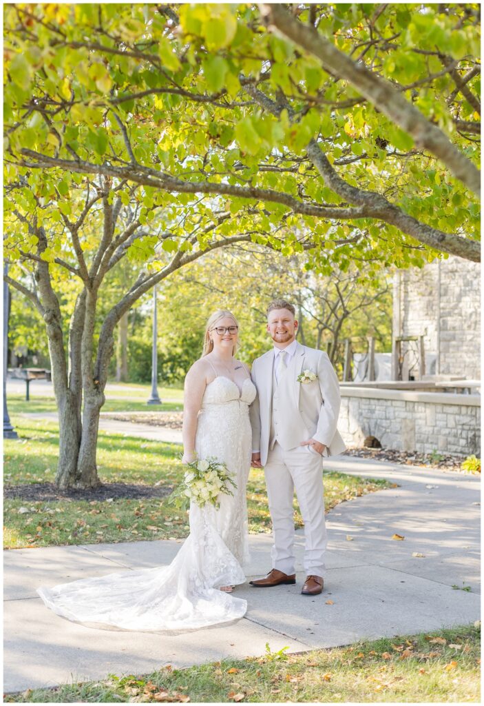 wedding couple posing on the sidewalk outside of Thompson Stone Hall