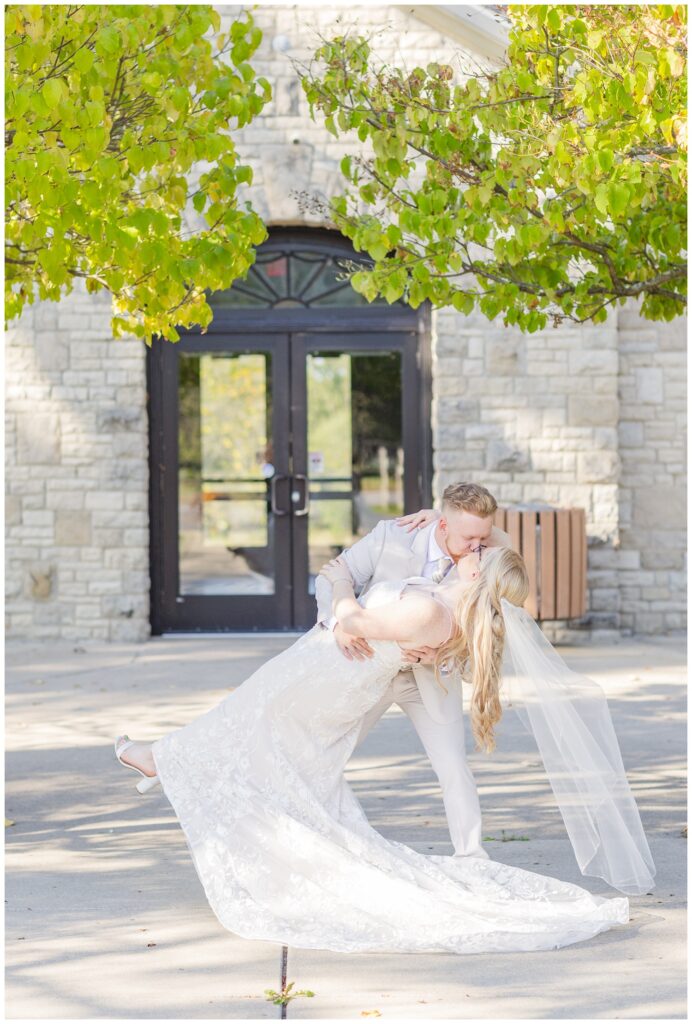 groom dipping the bride back for a kiss on the sidewalk outside of Thompson Stone Hall