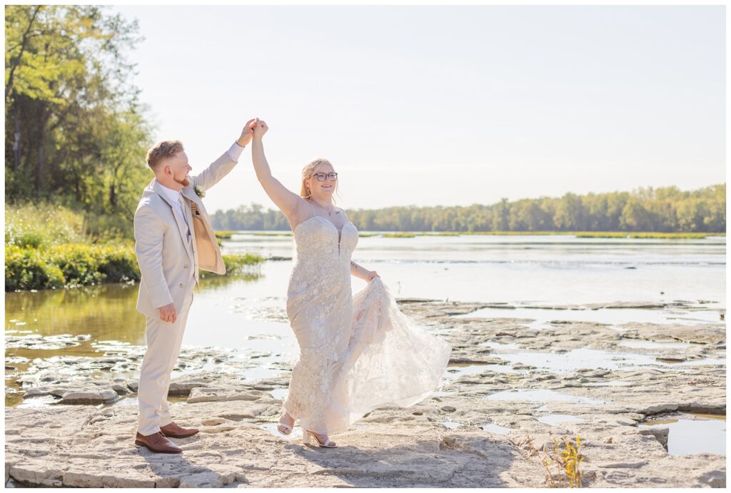 groom twirling the bride on the rocks in Otsego Park next to the river