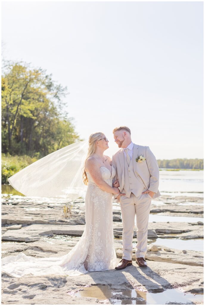 bride and groom smiling at each other next to the river in Bowling Green, Ohio