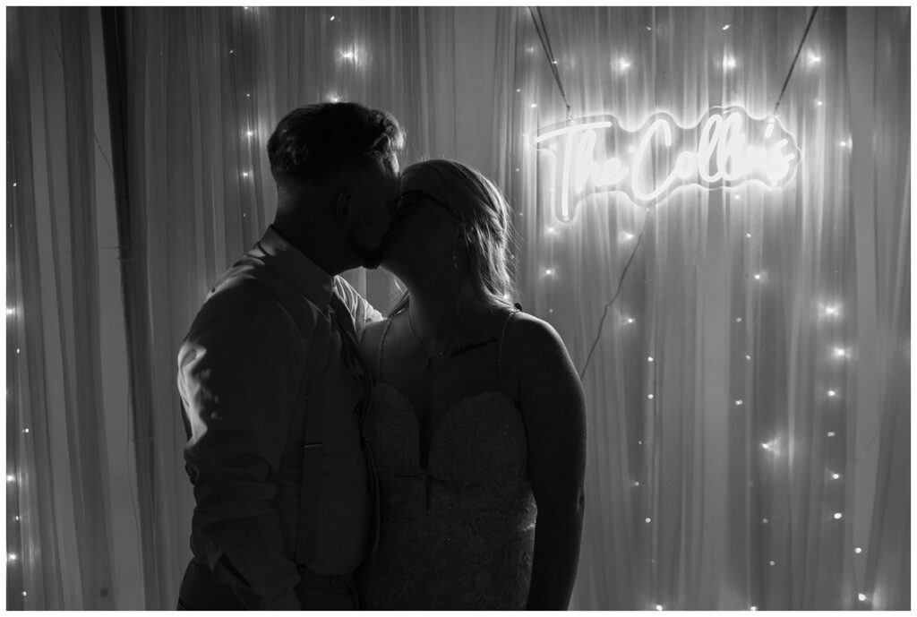 silhouette of the bride and groom in front of their neon sign showing their last name