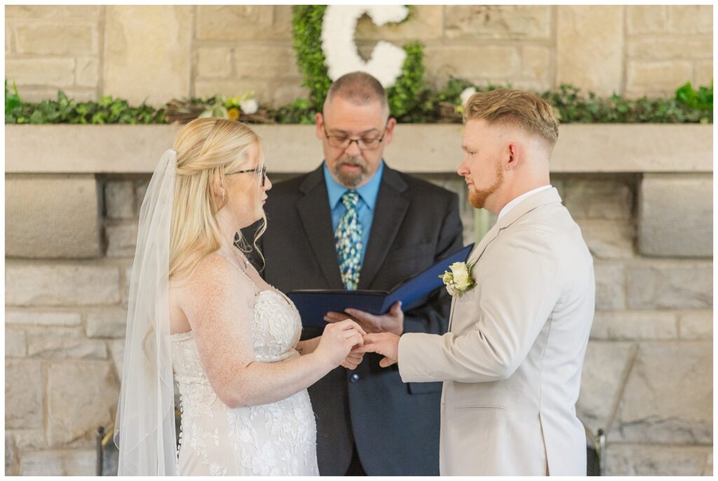 wedding couple exchanging rings at Thompson Stone Hall in Otsego Park 