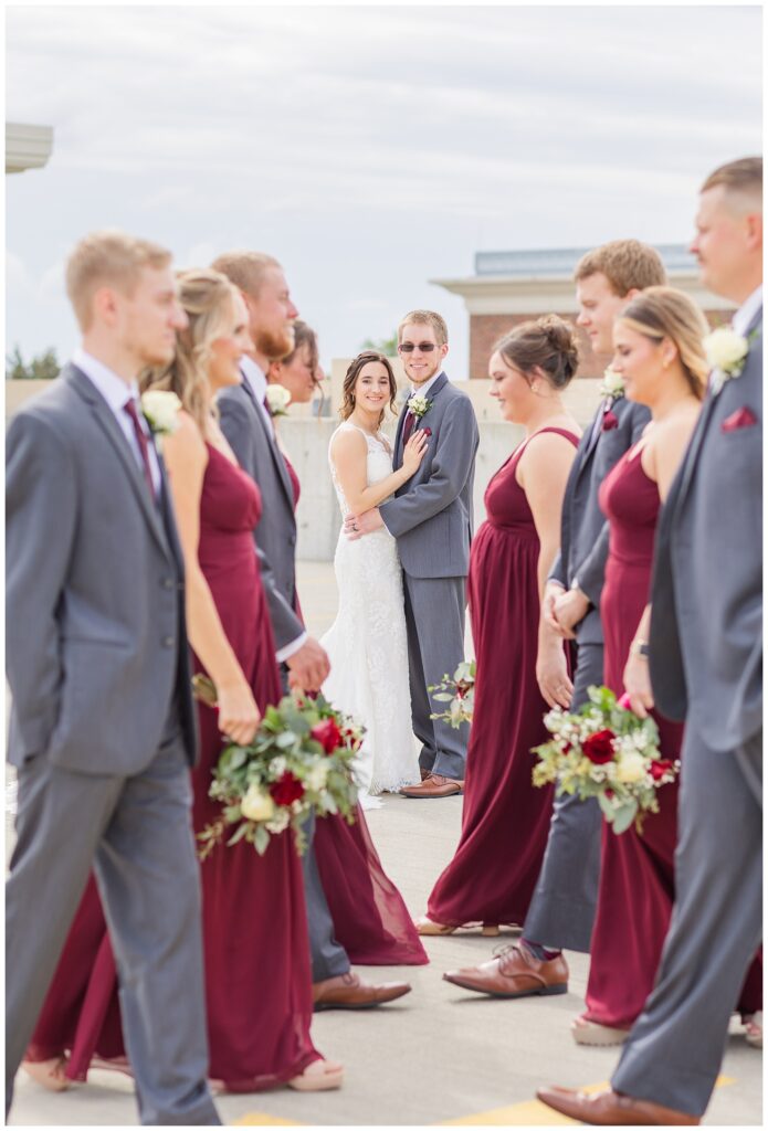 wedding couple standing still while the bridal party crosses in front of them