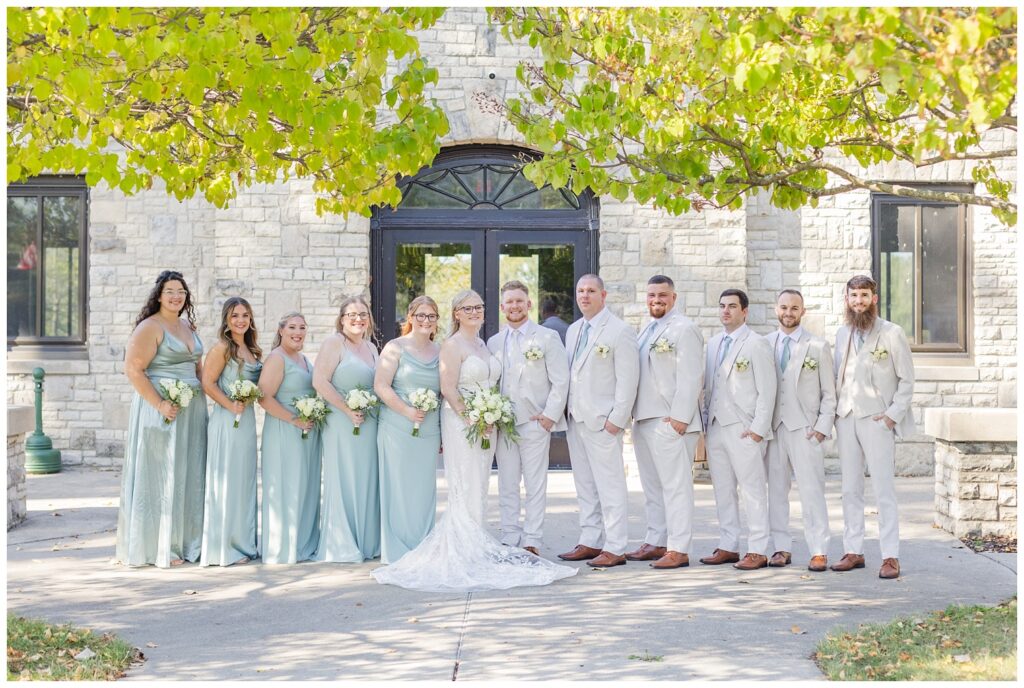 full wedding party posing outside of Thompson Stone Hall in the fall