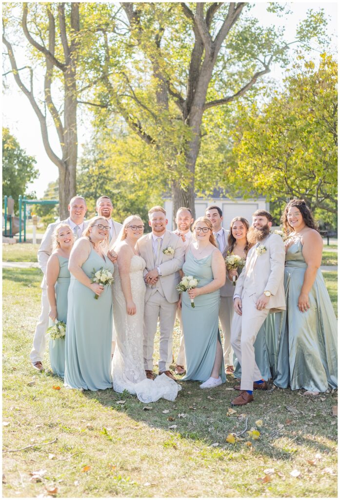 wedding party posing together on the lawn outside Thompson Stone Hall in Otsego Park