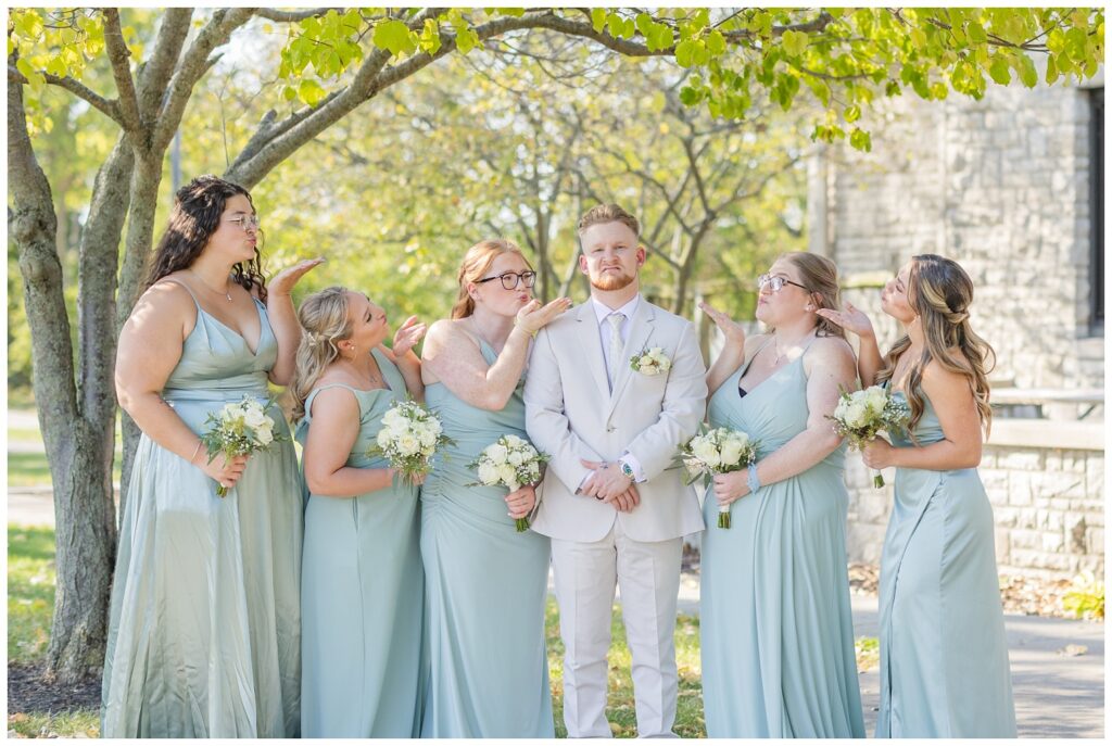 bridesmaids blowing kisses at the groom while he makes a funny face