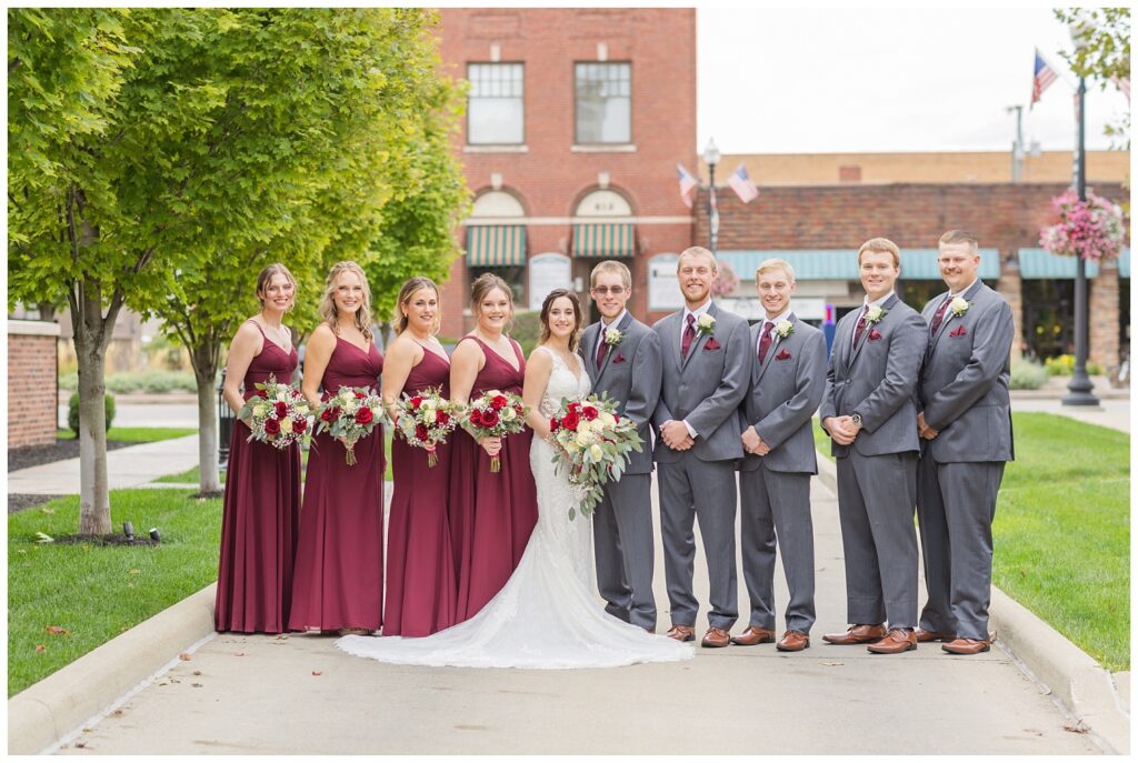 full wedding party posing on the sidewalk in downtown Findlay, Ohio