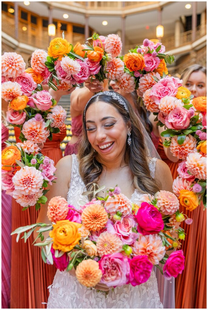 bride holding her bouquet while bridesmaids pose their bouquets around her face