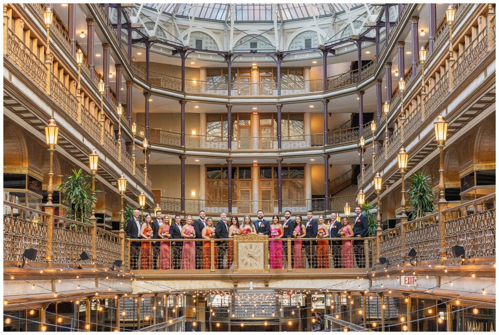 full wedding party posing in a line on the middle balcony at the Arcade Cleveland venue