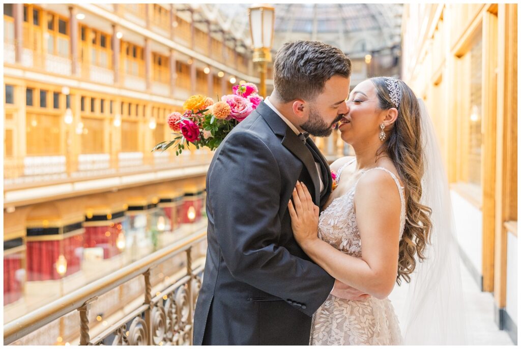 bride kissing groom on the balcony next to the shops at the Arcade