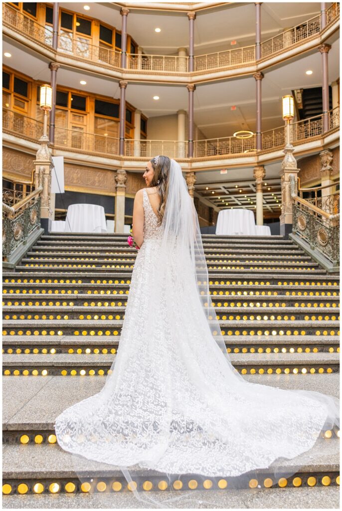 bride standing on the stairs showing the back of her dress holding her bouquet