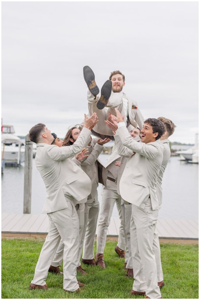 groomsmen throwing the groom up in the air near the water in Sandusky, Ohio