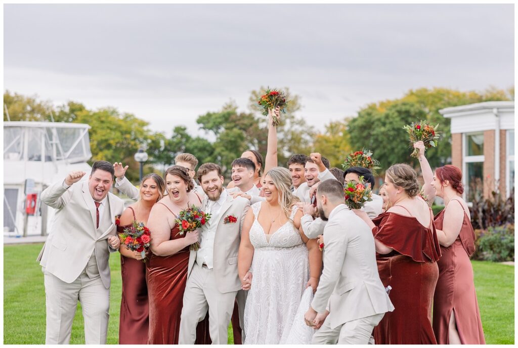 full wedding party cheering on the bride and groom in a big group together