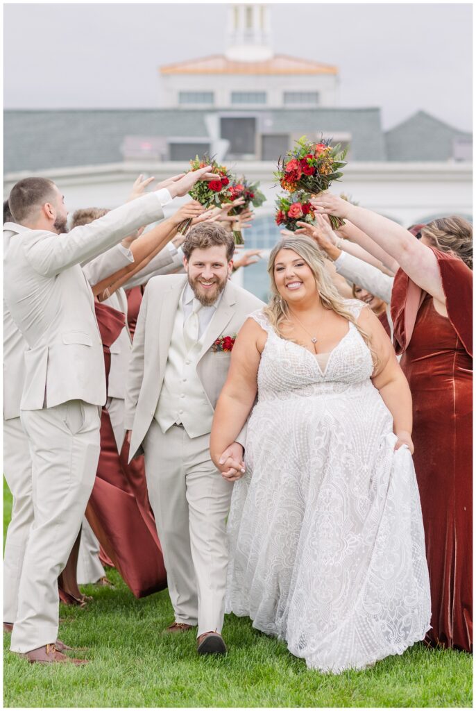 wedding couple going under a tunnel made by the bridesmaids and groomsmen