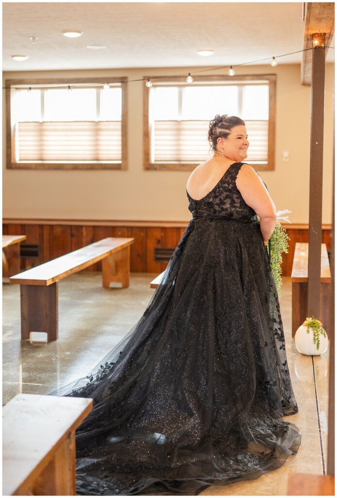 bride showing off the back of her black lace wedding dress inside at the chapel