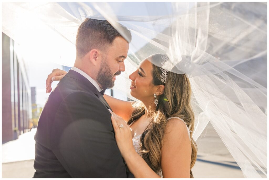 wedding couple posing under the bride's veil outside in downtown Cleveland