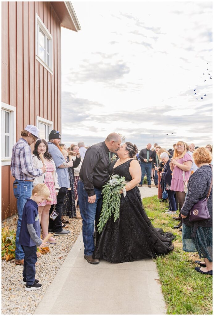 bride and groom walking down the sidewalk as wedding guests toss leaves at them