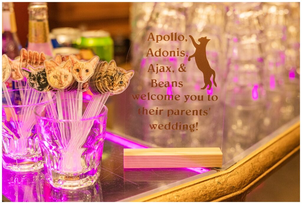 bar sign and cocktail stirs adorned with faces of the wedding couple's cats