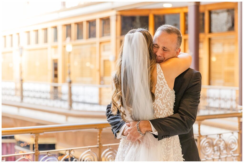 bride and her dad hugging during first look on the balcony of the Arcade Cleveland