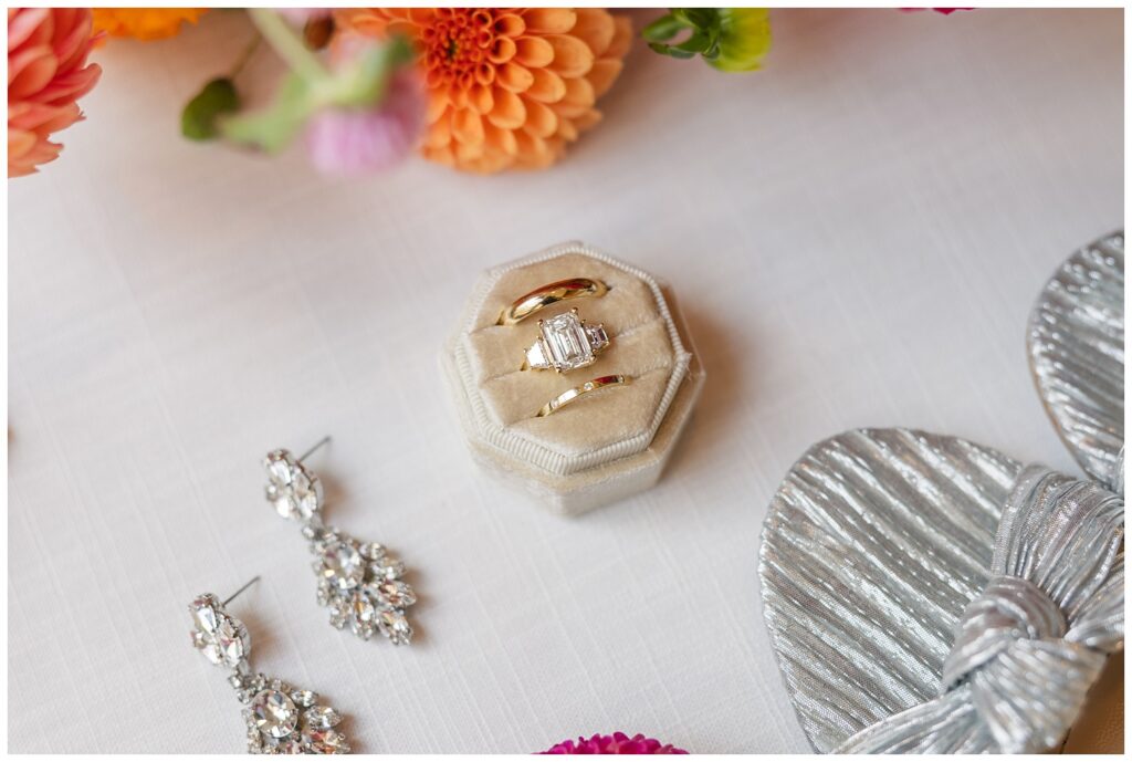 bride and groom's rings and earrings posed on a white flat lay mat next to shoes