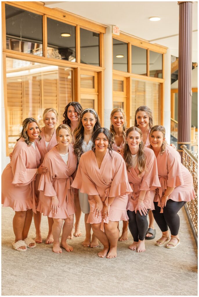 bride posing with her bridesmaids in robes on the balcony at the Arcade