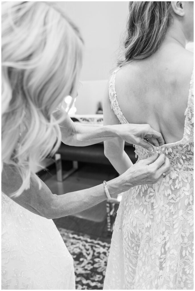 bride's mom zipping up the bride's lace dress at the Arcade