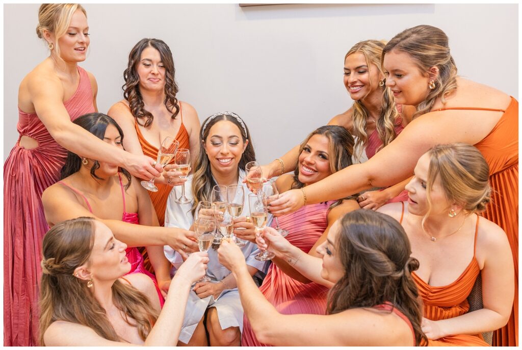 bride and bridesmaids toasting champagne while getting ready before the wedding