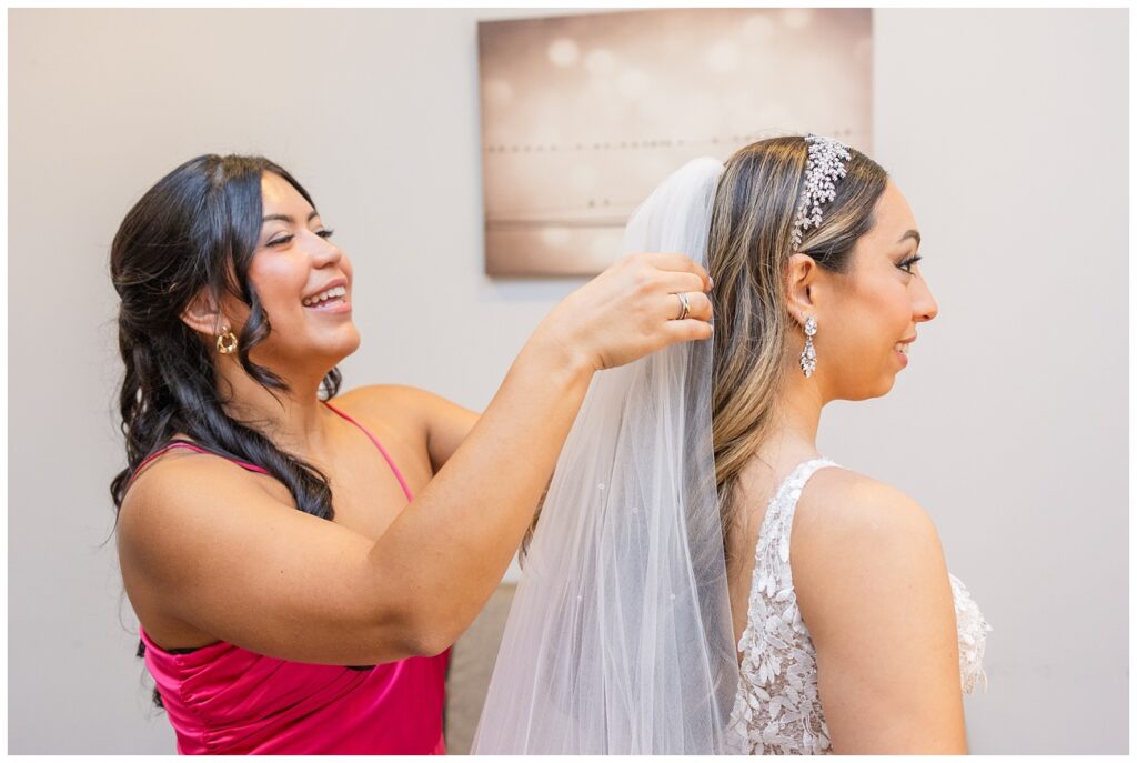 one the bridesmaids helping the bride adjust her veil while getting ready 