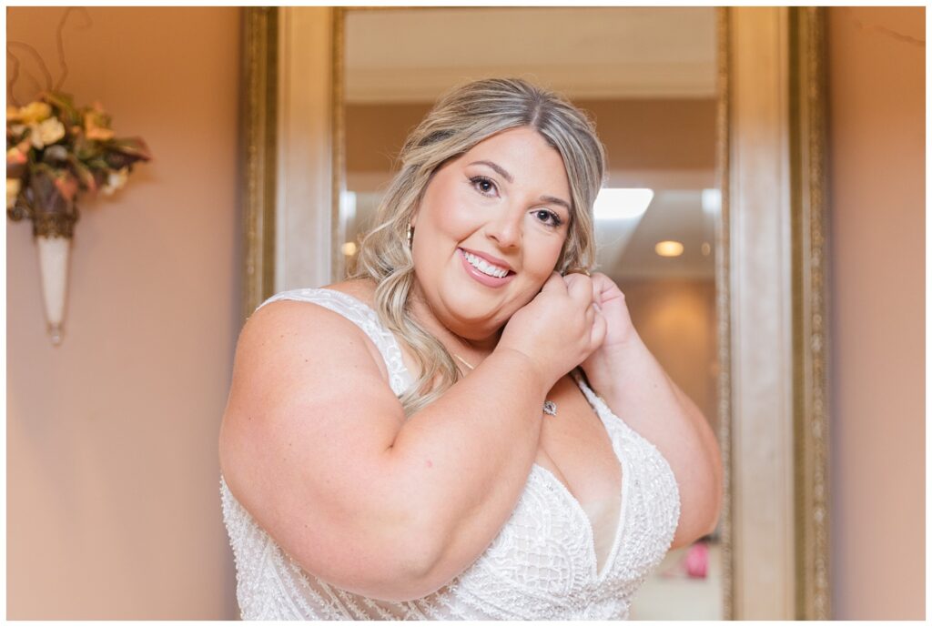 bride adjusting her earrings while getting ready at the church