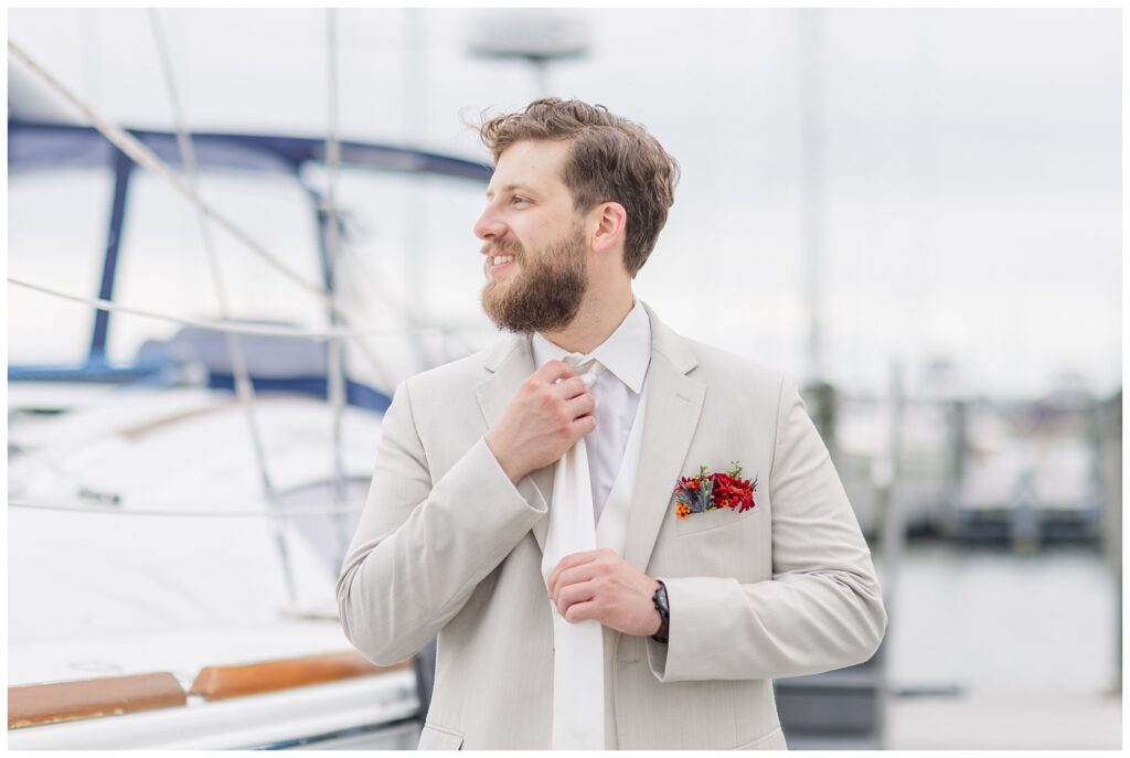 groom adjusting his tie on the gangway at the Sandusky Yacht Club next to the boats